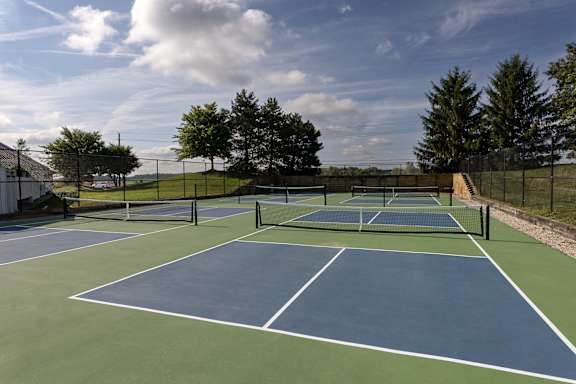 four pickleball courts on a blue and green court with trees in the background  at Latitudes Apartments, Indianapolis, IN, 46237