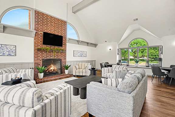 A community room with a fireplace and a television on the wall at Indian Lakes Apartments in Mishawaka, IN