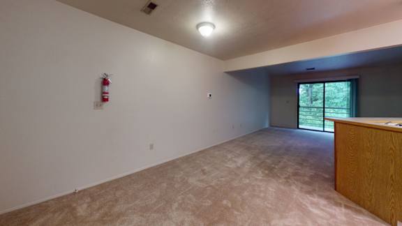 A dining and living room with sliding glass doors to a balcony at Indian Lakes Apartments, Indiana