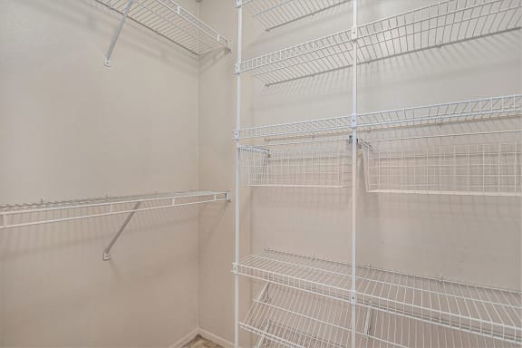 the walk in closet in the master bedroom has white wire shelves