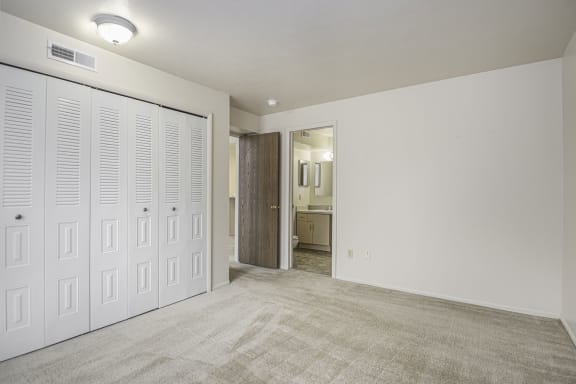an empty bedroom with white closets and a carpeted floor