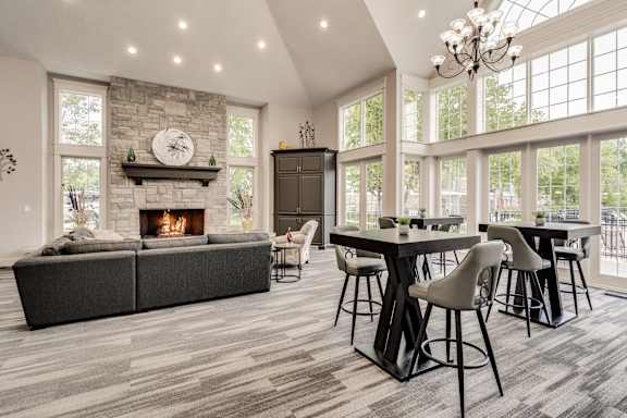 A modern dining room with a stone fireplace and a large table set for six at Westlake Apartments, Michigan