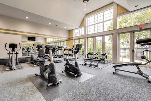 A gym with a variety of exercise equipment and a large window at Westlake Apartments, Michigan