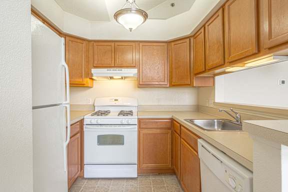 A kitchen with wooden cabinets and white appliances.