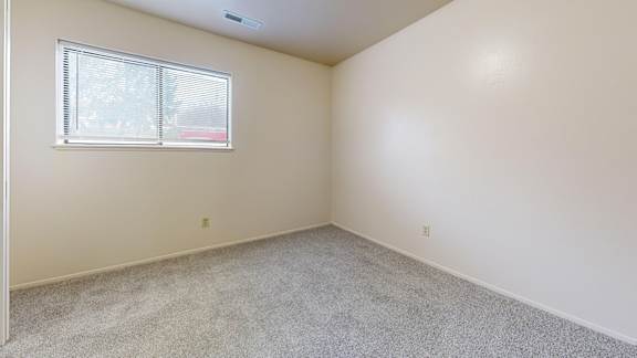 A bedroom with a window and carpeted floor at Irish Hills Apartments, South Bend, Indiana