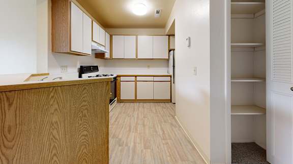 A kitchen with wooden cabinets and a pantry at Irish Hills Apartments, South Bend, Indiana