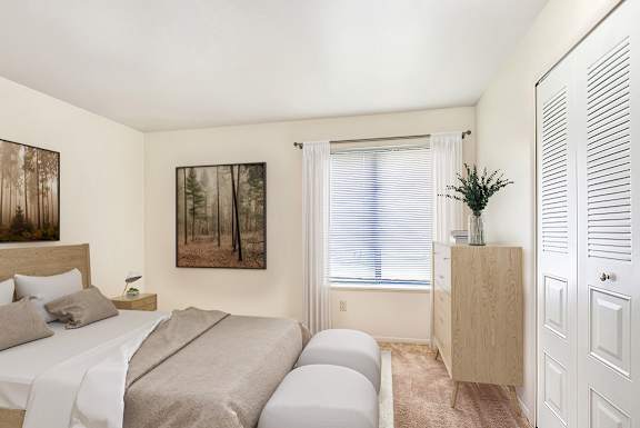 A bedroom with a bed, a nightstand, a cabinet, and a closet at Irish Hills Apartments, South Bend, Indiana
