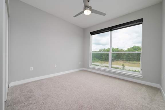 A room with a ceiling fan and a window overlooking a green landscape at Ironwood Flats Apartments, Florida, 33511