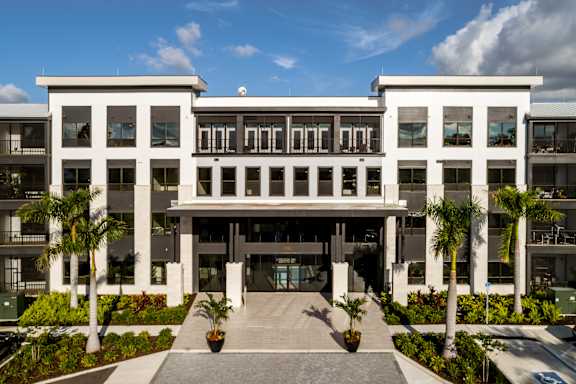 A modern building with a white facade and a central entrance at Ironwood Flats Apartments, Florida