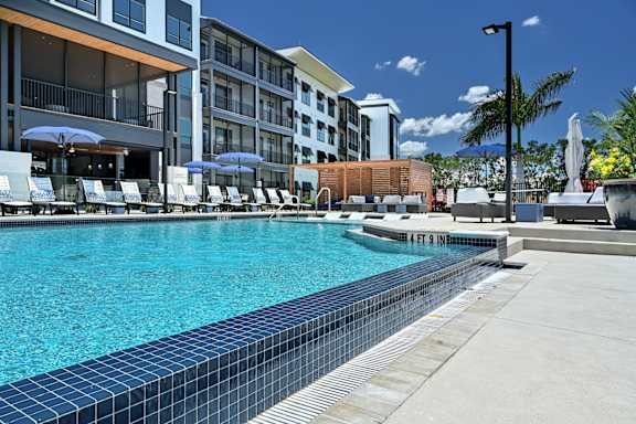A swimming pool in front of a hotel with a blue sky in the background at Ironwood Flats Apartments, Brandon