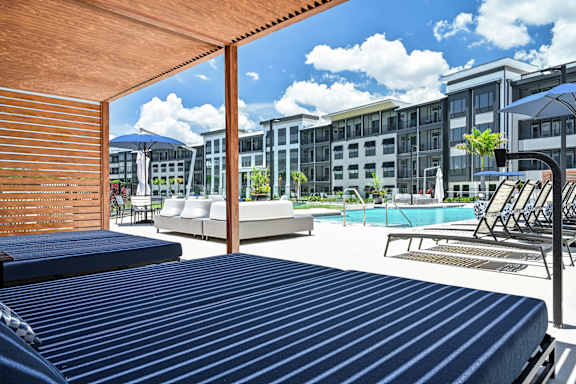 A pool area with sun loungers and a building in the background at Ironwood Flats Apartments, Brandon, FL