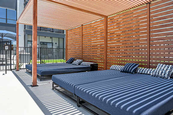 A wooden pergola with a striped bed underneath it at Ironwood Flats Apartments, Brandon, FL, 33511