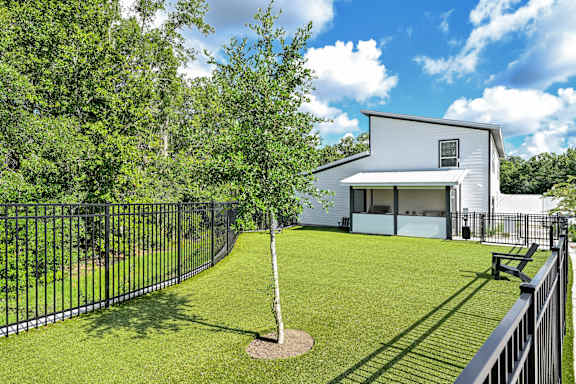 A white house with a black fence and a tree in the front yard at Ironwood Flats Apartments, Florida