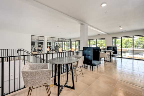 A modern living room with a black railing and a round table with chairs at Ironwood Flats Apartments, Brandon, 33511
