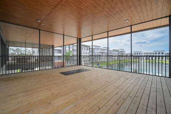 A room with wooden floors and a glass wall overlooking a grassy area.