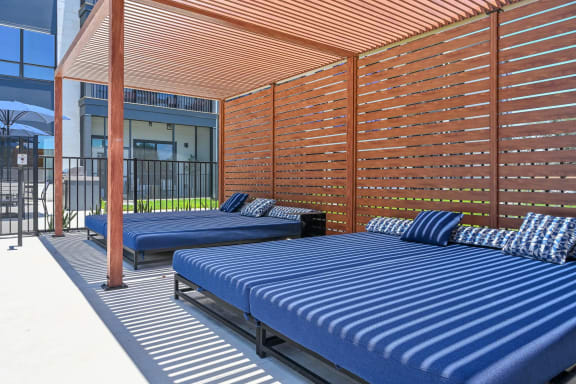 a patio with blue couches and a wooden pergola  at Ironwood Flats, Brandon