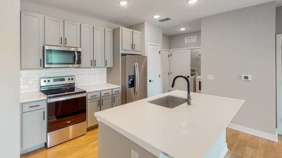 a kitchen with white cabinets and a large white island with a sink  at Ironwood Flats, Brandon, FL, 33511