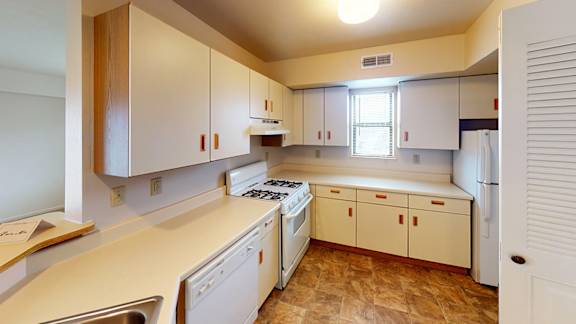 A kitchen with white appliances and wooden cabinets at Liberty Mills Apartments, Fort Wayne
