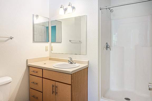 A bathroom with a sink, mirror, and a shower at Limestone Creek Apartment Homes, Madison, AL