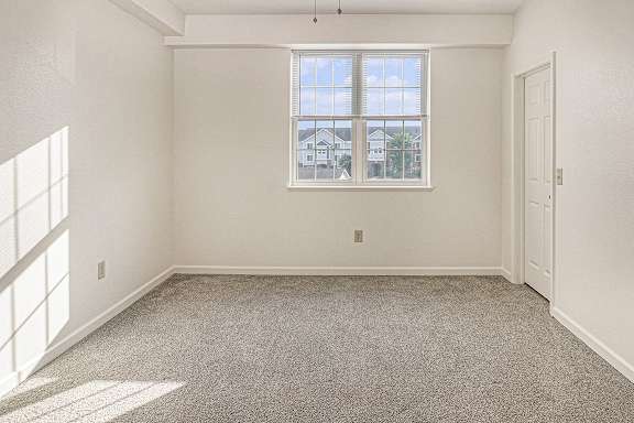 A bedroom with a large window, carpeted floor and a door to a walk-in closet at Limestone Creek Apartment Homes, Madison, AL