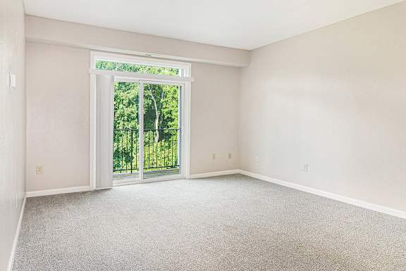 A living room with a 9 foot ceiling and a sliding glass door leading to a balcony at Limestone Creek Apartment Homes, Madison, AL