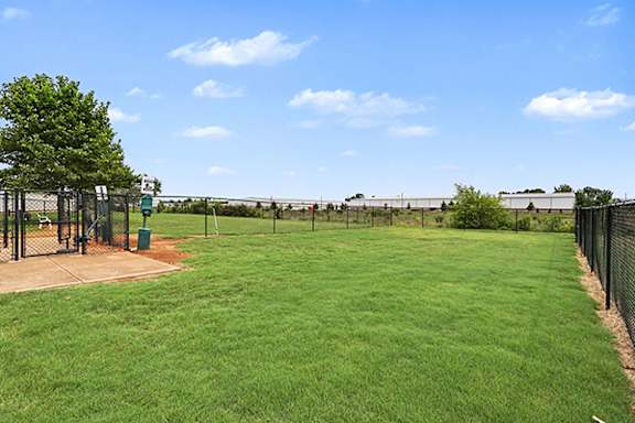 A dog park with a green field with a fence and a tree at Limestone Creek Apartment Homes, 35756