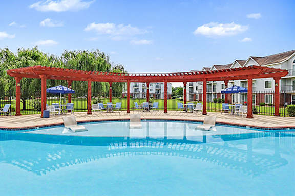A pool with a pergola and chairs around it at Limestone Creek Apartment Homes, 35756