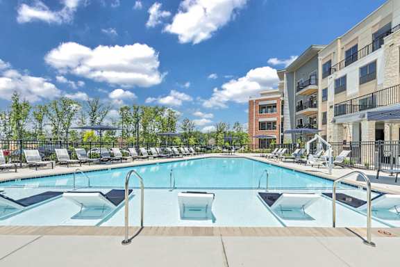 A large outdoor swimming pool with a metal ladder and a metal fence at Luxe 360 on Centerpointe Apartments, Virginia, 23114