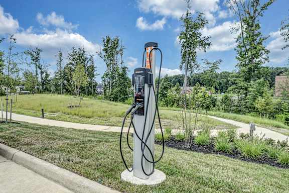 An electric vehicle charging station is on a concrete pad in a grassy area
