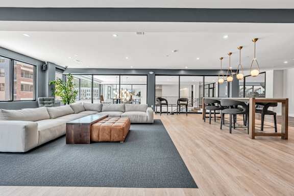 A modern living room with a grey sofa, a wooden coffee table, and a black rug at Luxe 360 on Centerpointe Apartments, Midlothian, VA