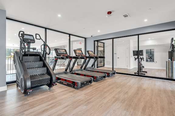 A gym with treadmills, elliptical machines, and a stair climber at Luxe 360 on Centerpointe Apartments, Midlothian, VA, 23114