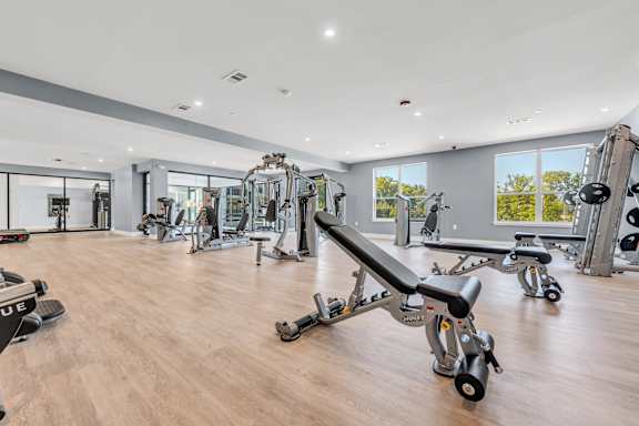 A gym with a variety of equipment including a bench press at Luxe 360 on Centerpointe Apartments, Virginia