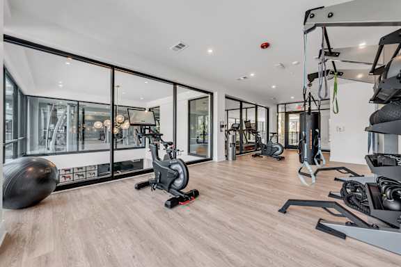 A gym with a variety of equipment including a stationary bike, a treadmill, and a rowing machine at Luxe 360 on Centerpointe Apartments, Midlothian, VA