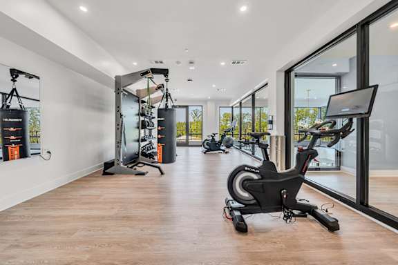 A gym with a row of exercise bikes and a row of pull up bars at Luxe 360 on Centerpointe Apartments, Midlothian, 23114
