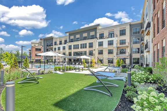 A sunny day at a modern apartment complex with a green lawn and a pool at Luxe 360 on Centerpointe Apartments, Midlothian, VA, 23114
