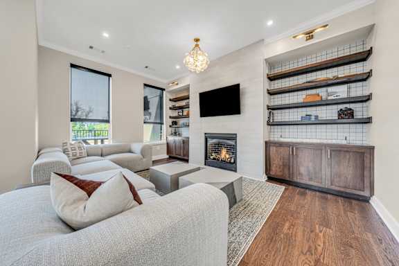 A modern living room with a grey couch and a fireplace at Luxe 360 on Centerpointe Apartments, Midlothian, VA
