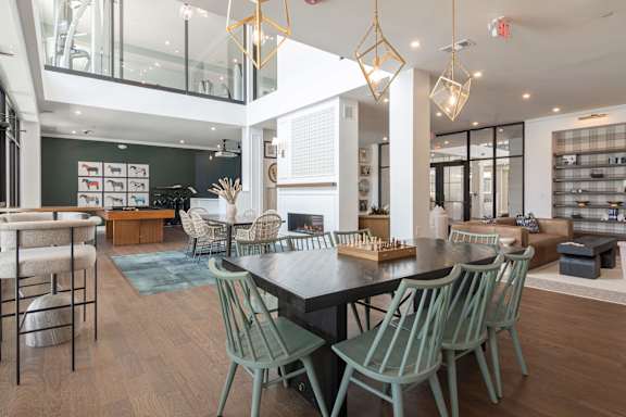 A modern dining room with a black table and green chairs at Luxe 360 on Centerpointe Apartments, Virginia, 23114