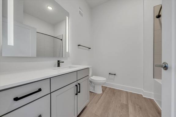 A white bathroom with a toilet, sink, and mirror at Luxe 360 on Centerpointe Apartments, Midlothian