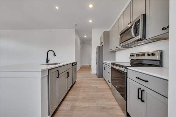 A modern kitchen with a white countertop and stainless steel appliances at Luxe 360 on Centerpointe Apartments, Virginia