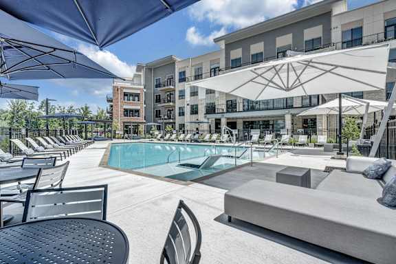 A pool area with a table and chairs and umbrellas