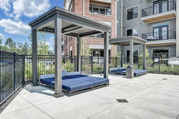 A concrete patio with a blue mattress and a black fence