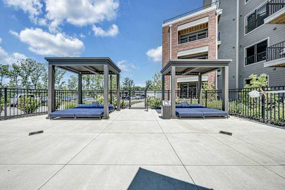 A concrete patio with two gazebos and a building in the background