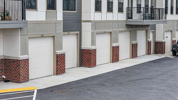 A street view of a row of garages with a car parked on the right side