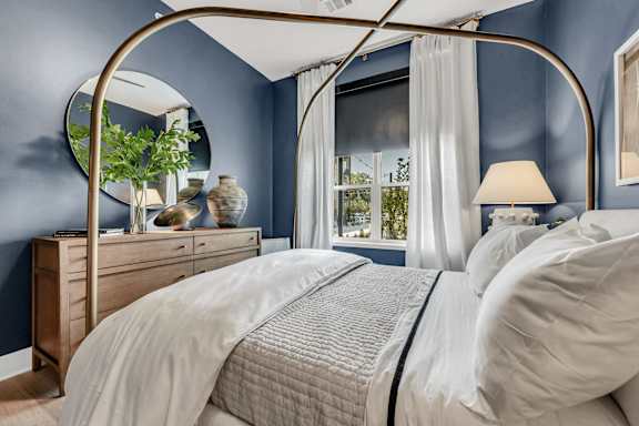 A bed with a canopy and a white bedspread in a room with blue walls at Luxe 360 on Centerpointe Apartments, Midlothian