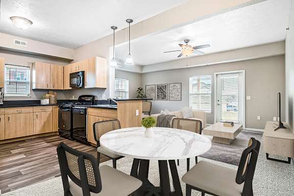 A dining room and kitchen with wooden cabinets and a black stove at Lynbrook Apartments and Townhomes, Elkhorn, NE, 68022.