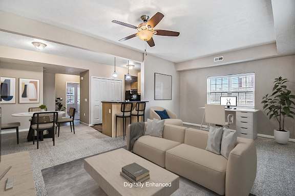 A living room with a beige couch and a ceiling fan A living room with a beige couch and a ceiling fan at Lynbrook Apartments and Townhomes, Elkhorn, NE, 68022