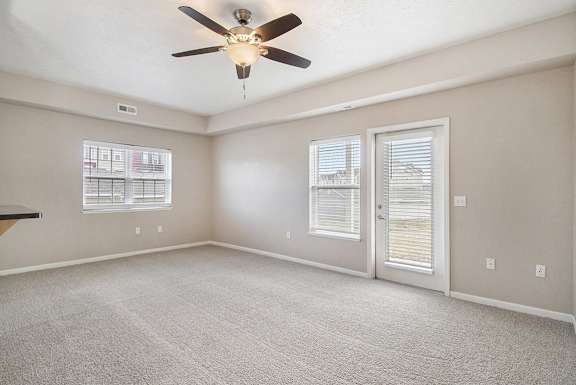 An end style living room with a ceiling fan and carpeted floor An end style living room with a ceiling fan and carpeted floor at Lynbrook Apartments and Townhomes, Elkhorn, NE, 68022