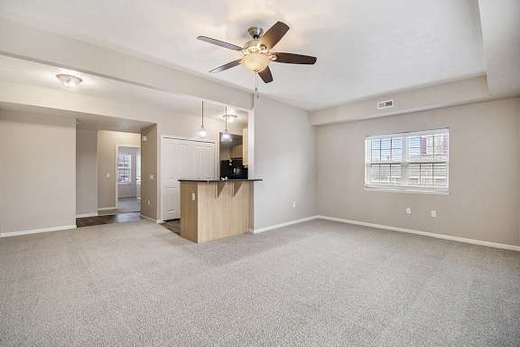 An end style living room with a carpeting, a ceiling fan, and a window with blinds An end style living room with a carpeting, a ceiling fan, and a window with blinds at Lynbrook Apartments and Townhomes, Elkhorn, NE, 68022