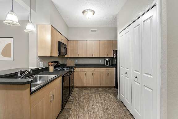A kitchen with wooden cabinets and a black counter top at Lynbrook Apartments and Townhomes, Elkhorn, NE, 68022