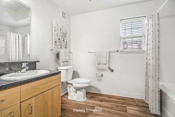 A bathroom with a toilet, sink, and a window A bathroom with a toilet, sink, and a window at Lynbrook Apartments and Townhomes, Elkhorn, NE, 68022